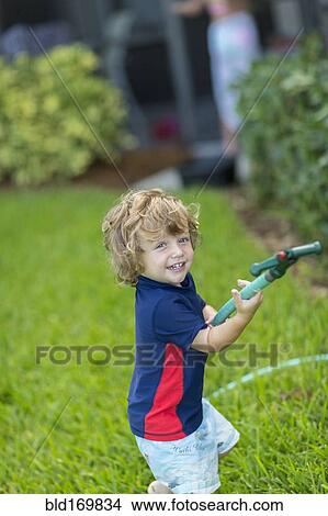 Caucasian baby boy playing with hose in backyard View Large Photo Image Picture - Caucasian baby boy playing with hose in backyard. Fotosearch