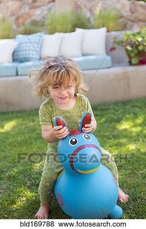 Stock Photo - Caucasian baby boy playing with toy in backyard. Fotosearch