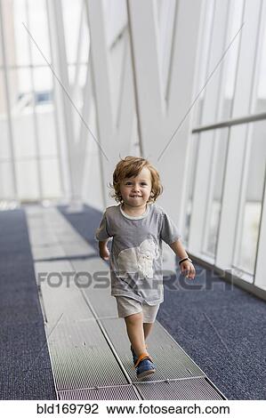 Stock Image - Caucasian baby boy walking in airport. Fotosearch