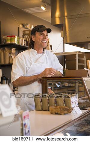Stock Image - Caucasian baker working in bakery. Fotosearch