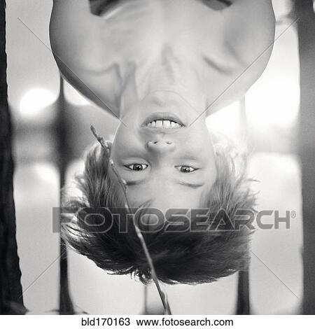 Stock Image - Caucasian boy hanging upside-down. Fotosearch