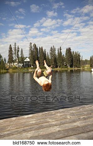 Stock Image - Caucasian boy jumping into lake. Fotosearch