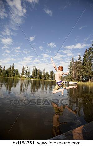 Stock Image - Caucasian boy jumping into lake. Fotosearch