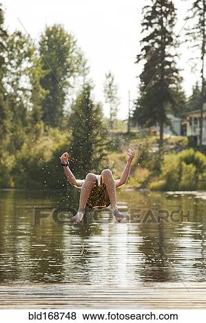 Stock Photo - Caucasian boy jumping into lake. Fotosearch