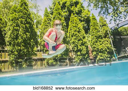Stock Image - Caucasian boy jumping into swimming pool. Fotosearch