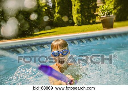 Stock Photo - Caucasian boy playing with squirt gun in swimming pool. Fotosearch