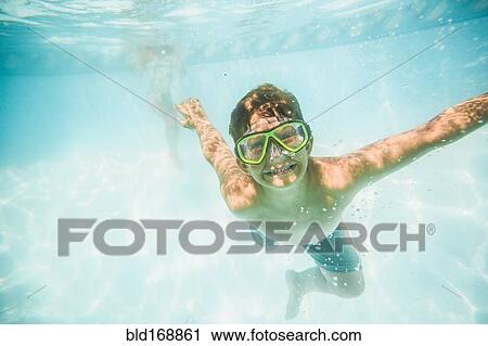 Stock Image - Caucasian boy swimming underwater in swimming pool. Fotosearch