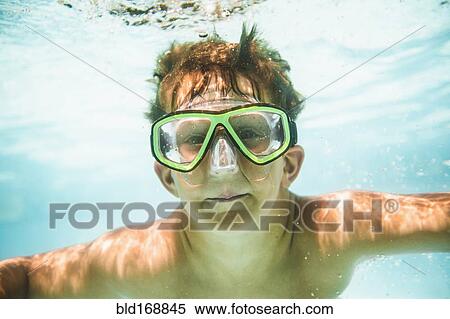 Stock Photography - Caucasian boy swimming underwater in swimming pool. Fotosearch