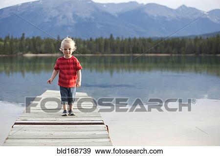 Stock Photo - Caucasian boy walking on dock over remote lake. Fotosearch