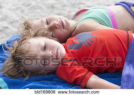 Stock Photo - Caucasian brother and sister napping on beach. Fotosearch