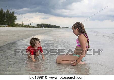 Stock Image - Caucasian brother and sister playing in ocean. Fotosearch