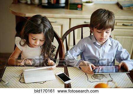Caucasian brother and sister using digital tablets View Large Photo Image Stock Image - Caucasian brother and sister using digital tablets. Fotosearch