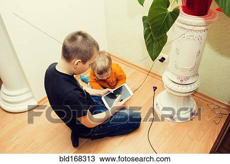 Caucasian brothers using digital tablet on floor View Large Photo Image Stock Image - Caucasian brothers using digital tablet on floor. Fotosearch