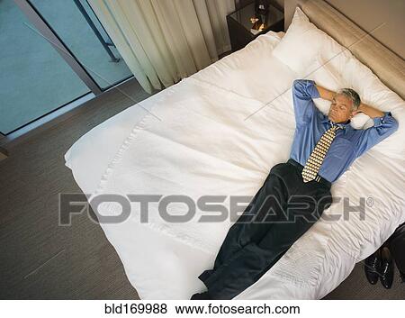 Caucasian businessman laying on hotel bed View Large Photo Image Stock Photo - Caucasian businessman laying on hotel bed. Fotosearch