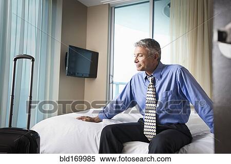Caucasian businessman sitting on hotel bed View Large Photo Image Stock Photography - Caucasian businessman sitting on hotel bed. Fotosearch