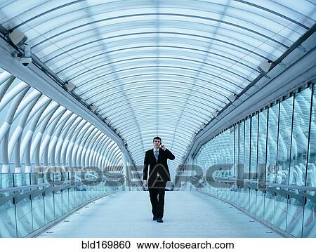 Stock Image - Caucasian businessman talking on cell phone in tunnel. Fotosearch