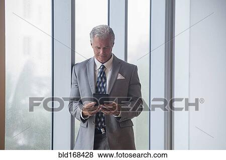 Stock Photo - Caucasian businessman using digital tablet near window. Fotosearch