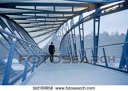 Stock Photo - Caucasian businessman walking on sky bridge. Fotosearch