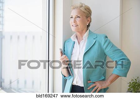 Stock Photo - Caucasian businesswoman looking out office window. Fotosearch