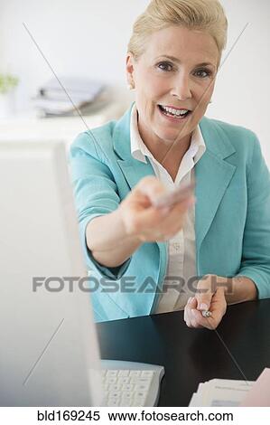 Stock Photography - Caucasian businesswoman offering business card in office. Fotosearch