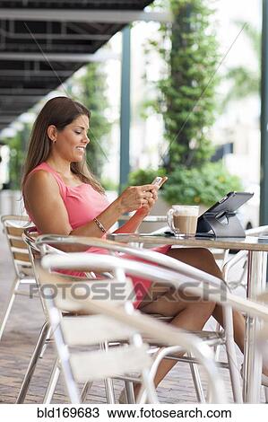 Stock Image - Caucasian businesswoman using cell phone at cafe. Fotosearch