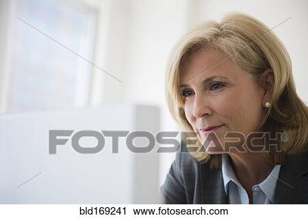 Stock Image - Caucasian businesswoman working on computer in office. Fotosearch