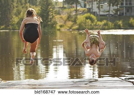 Stock Photo - Caucasian children jumping into lake. Fotosearch