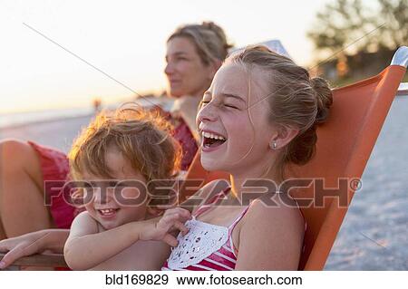Stock Photo - Caucasian children relaxing in lawn chair on beach. Fotosearch