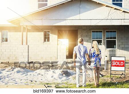 Stock Photo - Caucasian couple admiring new home. Fotosearch