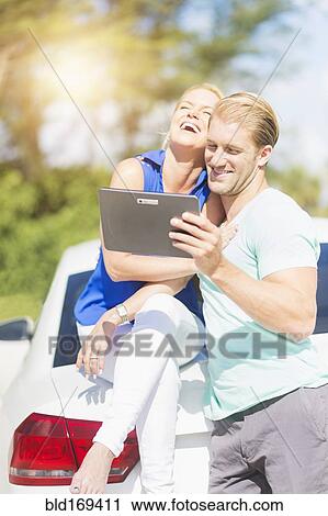 Caucasian couple at car using digital tablet View Large Photo Image Stock Image - Caucasian couple at car using digital tablet. Fotosearch