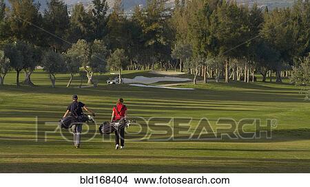 Caucasian couple carrying golf bags on course View Large Photo Image Picture - Caucasian couple carrying golf bags on course. Fotosearch