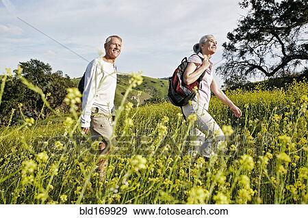 Stock Photo - Caucasian couple hiking in tall grass. Fotosearch