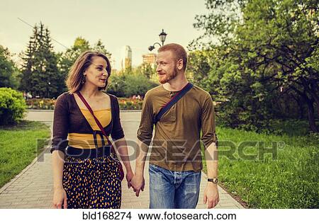 Caucasian couple holding hands in park View Large Photo Image Picture - Caucasian couple holding hands in park. Fotosearch