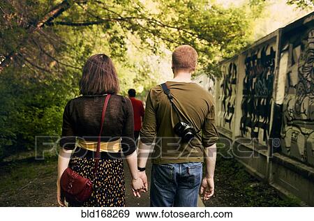 Stock Photo - Caucasian couple holding hands in urban park. Fotosearch