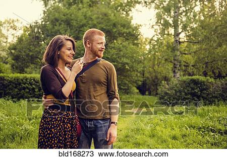 Stock Image - Caucasian couple hugging in field. Fotosearch