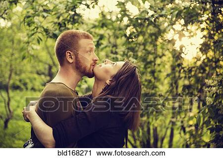 Stock Image - Caucasian couple hugging near trees. Fotosearch