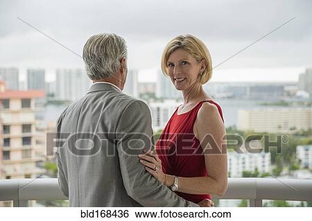 Stock Photograph - Caucasian couple hugging on balcony. Fotosearch
