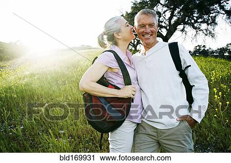 Stock Image - Caucasian couple kissing in tall grass. Fotosearch