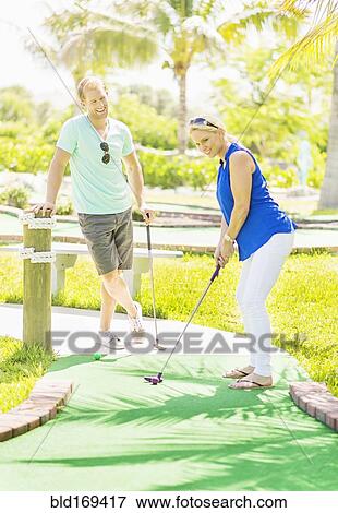 Stock Photo - Caucasian couple playing miniature golf. Fotosearch