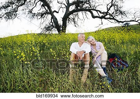 Picture - Caucasian couple sitting in tall grass. Fotosearch