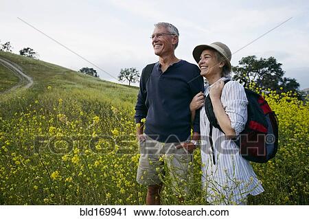 Stock Image - Caucasian couple standing in tall grass. Fotosearch