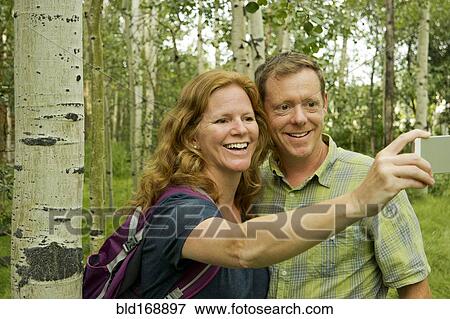 Caucasian couple taking self-portrait in forest View Large Photo Image Stock Photo - Caucasian couple taking self-portrait in forest. Fotosearch