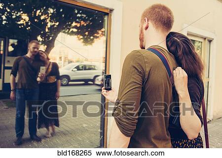 Stock Photography - Caucasian couple taking self portrait in mirror. Fotosearch