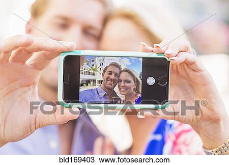 Stock Image - Caucasian couple taking selfie on cell phone. Fotosearch