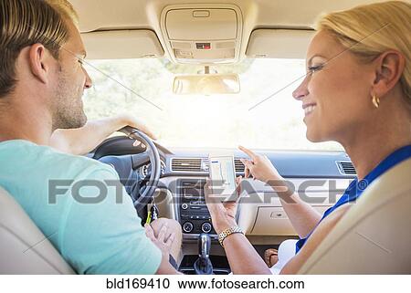 Stock Image - Caucasian couple using cell phone navigation in car. Fotosearch