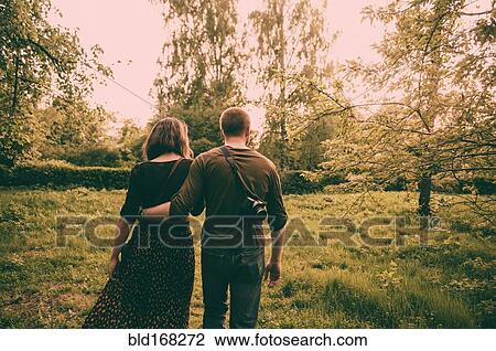 Stock Image - Caucasian couple walking in field. Fotosearch