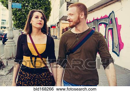 Stock Photograph - Caucasian couple walking on city sidewalk. Fotosearch