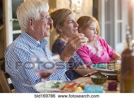 Stock Photograph - Caucasian family eating at table outdoors. Fotosearch