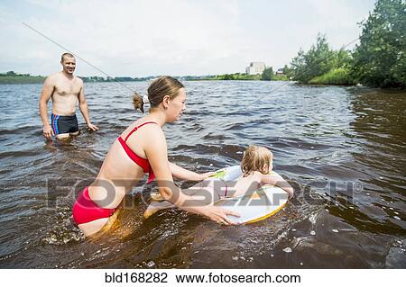 Stock Image - Caucasian family swimming in lake. Fotosearch