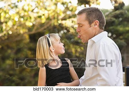 Stock Image - Caucasian father and daughter sticking out tongues. Fotosearch